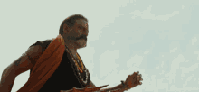a man in a red cape is holding a spear with the website namdamusfans.com in the lower right corner