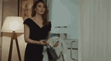 a woman in a black dress is standing in front of a door .