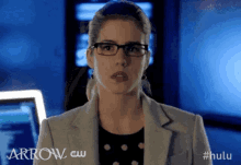 a woman wearing glasses is standing in front of a blue background .