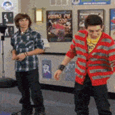 two young men are dancing in front of a kung fu poster on the wall .