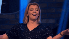 a woman in a polka dot shirt is smiling in front of a tv screen