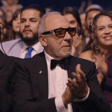 a man in a tuxedo applauds in a crowd