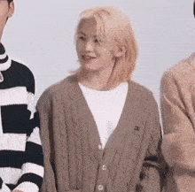 a man with blonde hair is wearing a cardigan