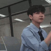a man in a blue shirt and tie is covering his nose with his finger