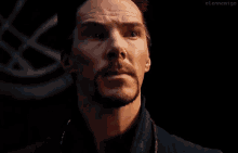 a close up of a man 's face with a beard in a dark room