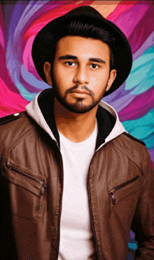 a man with a beard wearing a hat and a leather jacket
