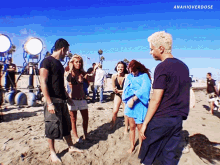 a group of people standing on a beach with a blue sky in the background