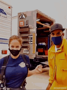 a woman wearing a mask stands next to a man wearing a mask in front of a truck that says swat on it