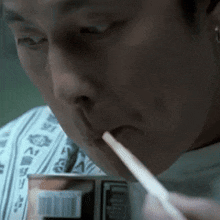 a man is drinking from a can with a straw