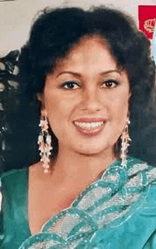a woman is wearing a green dress and earrings and smiling .