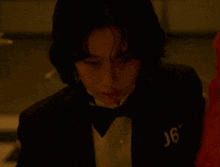 a man in a tuxedo and bow tie has the number j67 on his chest