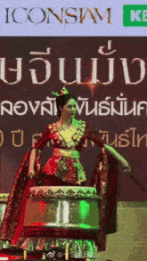 a woman playing a drum in front of a sign that says iconsam