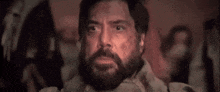 a man with a beard is sitting in a dark room with the words `` baba booey '' written on his face .