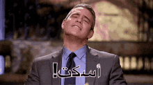 a man in a suit and tie is making a funny face with arabic writing on his face .