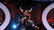 a wrestler with horns on his head is pointing at the camera