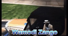 a man in a hat is driving a car with the words wamodi zango written on the bottom