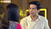 a man and a woman are looking at each other with a star plus advertisement in the background