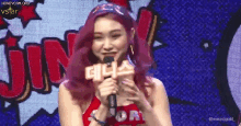 a woman with red hair is holding a microphone in front of a comic book background .