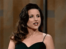 a woman in a black dress is standing in front of a wooden wall .