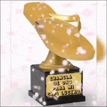 a gold flip flop is sitting on top of a trophy .