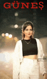 a woman in a black top and white pants stands in front of a sign that says " gunes "