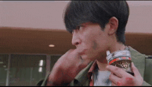 a young man is holding a can of soda in his hand and eating it .