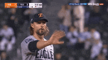 a baseball player wearing an eagle jersey stands in front of a screen that says sbs sports live