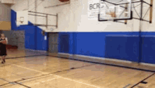 a person is playing basketball in a gym with a sign that says bcr on the wall