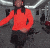 a woman in a red sweater and black shorts is standing in a room holding a gun .