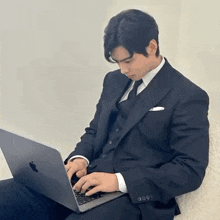 a man in a suit is typing on a laptop computer .