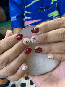 a person 's nails are painted red and white with a gold star and a ribbon