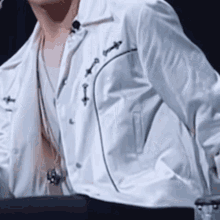 a man is wearing a white jacket and a white shirt .