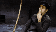 a man sitting on the ground with a cane and a hat on