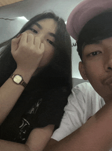 a girl wearing a watch and a boy wearing a pink hat pose for a picture