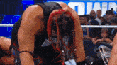 a wrestler with red dreadlocks is kneeling down in the ring .