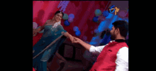 a man and a woman are dancing on a stage with balloons in the background .
