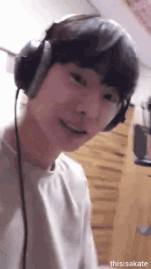 a young man is wearing headphones and smiling .