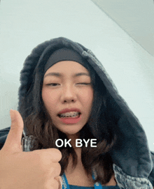 a girl with braces on her teeth is giving a thumbs up and the words ok bye are above her head