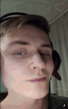a close up of a man wearing headphones and making a funny face
