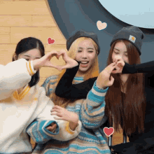 three girls are making a heart shape with their fingers