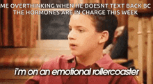a boy in a red shirt is sitting at a table and talking to another boy .