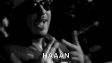 a man wearing sunglasses is singing into a microphone .