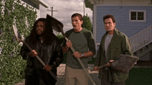 three men holding shovels and rakes in front of a house