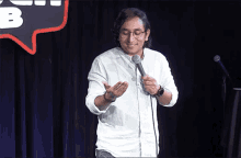 a man stands in front of a microphone in front of a speech bubble with the letter b