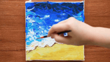 a person is painting a picture of a beach with a brush .