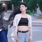 a woman wearing a crop top and a headband is walking down a street