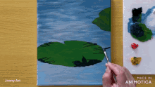 a painting of a lily pad is being painted on a canvas by joany art