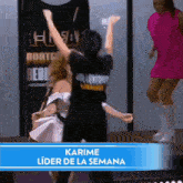 a woman in a pink dress is dancing with a man in a black shirt that says karime lider de la semana