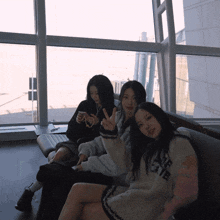three girls are sitting on a couch with one wearing a sweater that says " air "