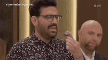 a man wearing glasses and a shirt that has smiley faces on it is on a television show called masterchef argentina